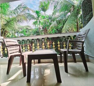 two chairs and a table on a balcony with palm trees at Hotel Adam's Baga Beach Resort Goa - 2 minutes walk from Baga Beach in Baga