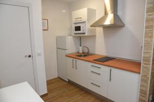 Una cocina blanca con fregadero y microondas. en LA VILLA DE ORGAZ II, en Toledo