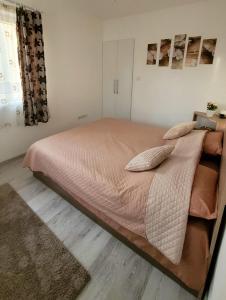 a bedroom with a large bed with pink sheets and pillows at Fortuna Park Apartman in Sfântu-Gheorghe