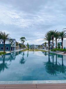 a large swimming pool with palm trees and houses at Novaworld Phan Thiết- 7Days mart in Phan Thiet