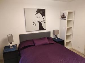 a bedroom with a bed with purple sheets and two lamps at Bastis Family Apartment in Lucerne