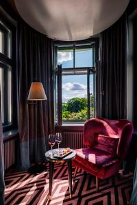 um quarto com uma cadeira vermelha, uma mesa e uma janela em Grand Poet Hotel and SPA by Semarah em Riga