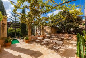 un patio con mesas y sillas bajo un árbol en Yartan Boutique Hotel - Adults Only, en Artà