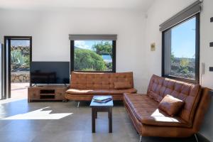 una sala de estar con 2 sofás de cuero marrón y una mesa. en Casa SAS La Hoya, en Yaiza