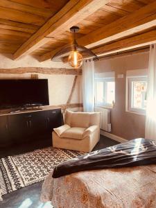 ein Wohnzimmer mit einem Sofa, einem TV und einem Stuhl in der Unterkunft LA MARIEFACTURE - Comm chez Mémé in Laning