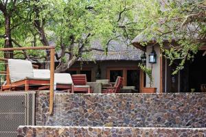 Casa con patio con sillas y pared de piedra. en Mount Marula Game Lodge - Tambotie, en Kwarriekraal