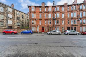 grupa samochodów zaparkowanych przed budynkiem w obiekcie Traditional 1-Bed Flat in Southside (Hampden/Shawlands) w Glasgow