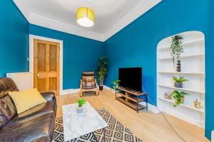 Sala de estar azul con sofá y TV en Traditional 1-Bed Flat in Southside (Hampden/Shawlands) en Glasgow