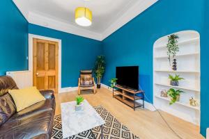 a blue living room with a couch and a tv at Traditional 1-Bed Flat in Southside (Hampden/Shawlands) in Glasgow