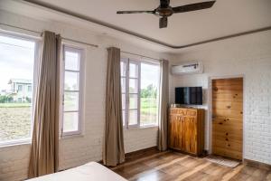 Schlafzimmer mit Fenstern, einem Bett und einem TV in der Unterkunft Hibiscus in Kota Bāgh