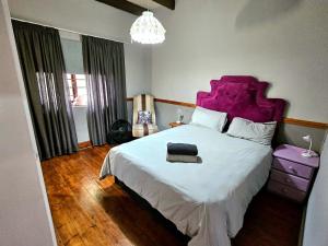 a bedroom with a large white bed with a purple headboard at Mosselbay Dream Home in Mossel Bay