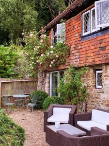 un bâtiment en briques avec deux chaises, une table et un banc dans l'établissement Strand House, à Winchelsea