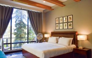 a bedroom with a bed and a large window at Lemon Lodges By Roomy, Nathiagali in Nathia Gali