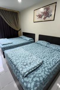 two beds in a hotel room with blue comforter at 西子楼 CZI Budget Hotel Sungai Siput in Sungai Siput