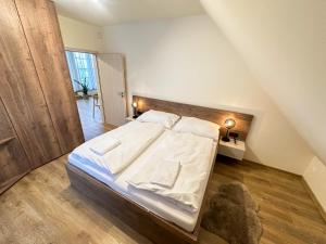 1 dormitorio con 1 cama con sábanas y almohadas blancas en Apartmány nad Anenským potokem - Říčky en Říčky