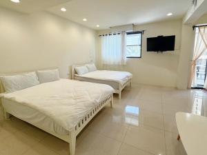 a bedroom with two beds and a tv on the wall at Kaohsiung Raifong Corner Homestay in Kaohsiung