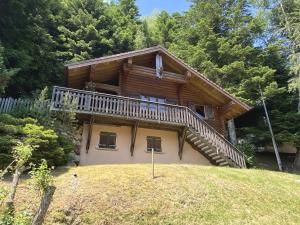 una casa de madera con una escalera en una colina en LE GRAND CERF Chalet en rondins avec SPA Jacuzzi en La Bresse