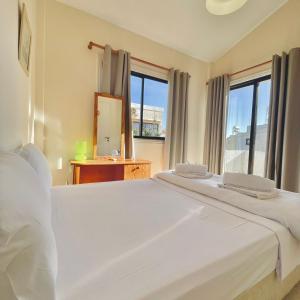 a bedroom with a large white bed with a large window at Merika Complex 1 in Pervolia