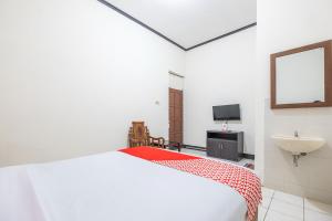 a white bedroom with a bed and a sink at SUPER OYO 2703 Hotel Transit 1 in Makassar