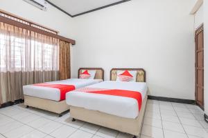 two beds in a room with red and white sheets at OYO 2703 Hotel Transit 1 in Makassar