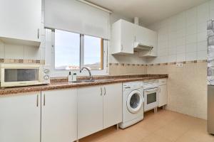 uma cozinha com armários brancos e uma máquina de lavar e secar roupa em Casa Axarquia em Vélez-Málaga