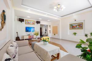 ein Wohnzimmer mit einem Sofa und einem Tisch mit Blumen in der Unterkunft Cát Tường Villa gần biển in Vũng Tàu