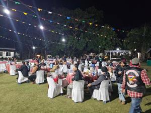 un gran grupo de personas sentadas en las mesas por la noche en Baan Rai Somkiat Homestay Saraburi, en Ban Lam Thong Lang