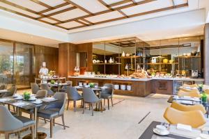 a restaurant with tables and chairs and a chef in the background at Marriott Executive Apartments Hangzhou Yuhang in Hangzhou