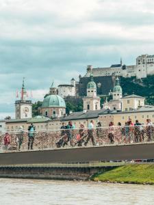 people walking across a bridge in front of a castle at Zimmer Flower Nähe Bahnhof & LKH in Salzburg