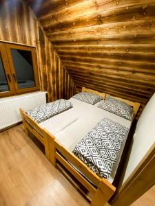 Bett in einem Zimmer mit einer Holzwand in der Unterkunft Chata TRI GROŠE 2 in Námestovo