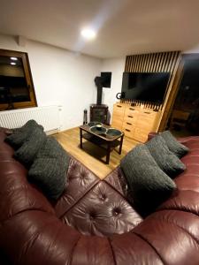 salon z brązową skórzaną kanapą z poduszkami w obiekcie Chata TRI GROŠE 2 w Namiestowie