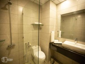 a bathroom with a toilet and a sink and a mirror at Roomy Signature Hotel, Islamabad in Islamabad