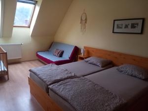 een slaapkamer met 2 bedden en een rode stoel bij Forrás Vendégház in Szálka
