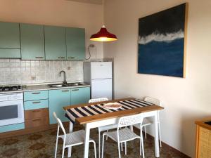 cocina con mesa, sillas y nevera en Be Your Home - Casa Raffaello, en Santa Marinella