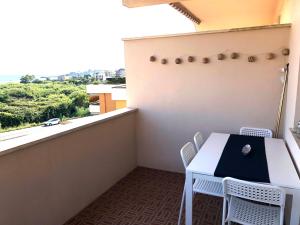 balcón con mesa, sillas y ventana en Be Your Home - Casa Raffaello, en Santa Marinella