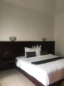 1 dormitorio con 1 cama blanca grande con almohadas blancas en Zifa Kuta Lombok, en Kuta Lombok