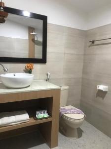 een badkamer met een wastafel, een toilet en een spiegel bij Zifa Kuta Lombok in Kuta Lombok