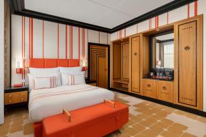 a bedroom with a bed and an orange ottoman at Dinamo Hotel Baku in Baku