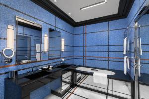 a blue tiled bathroom with a sink and mirrors at Dinamo Hotel Baku in Baku