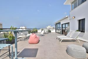 a patio with white chairs and a red bag on a building at ROOFTOP 42 - Penthouse in Haifa
