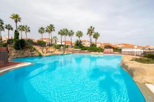 una grande piscina blu con palme sullo sfondo di Holiday Beach El Faro a Santa Pola
