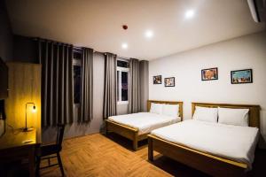 a bedroom with two beds and a desk and window at 1991 Boutique Hotel in Phan Thiet