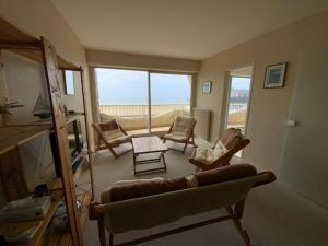 un salon avec un canapé et des chaises et une grande fenêtre dans l'établissement 451 - Appartement à ERQUY, en bordure de la très belle plage de CAROUAL, à Erquy