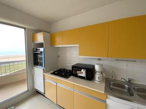 La cuisine est équipée de placards jaunes, d'un évier et d'un four micro-ondes. dans l'établissement 451 - Appartement à ERQUY, en bordure de la très belle plage de CAROUAL, à Erquy