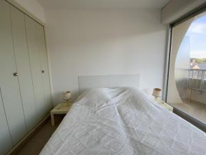une chambre blanche avec un lit et une fenêtre dans l'établissement 451 - Appartement à ERQUY, en bordure de la très belle plage de CAROUAL, à Erquy 2 autres photos