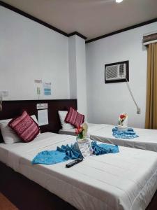 2 Betten in einem Hotelzimmer mit Blumen darauf in der Unterkunft D'Mariners Inn Hotel in Batangas City