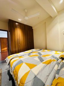 a bedroom with a bed with a yellow and white comforter at The Pent - Richmond in Bangalore