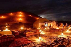 a tent in the desert at night with lights at Berber & Camel Trek in Merzouga