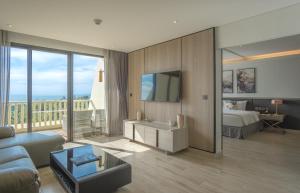 a hotel room with a bed and a tv and a living room at Paradox Resort Phuket in Karon Beach