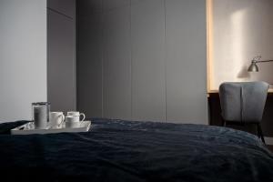 a bed with two cups and a tray on it at Apartament pod gwiazdką in Tomaszów Mazowiecki